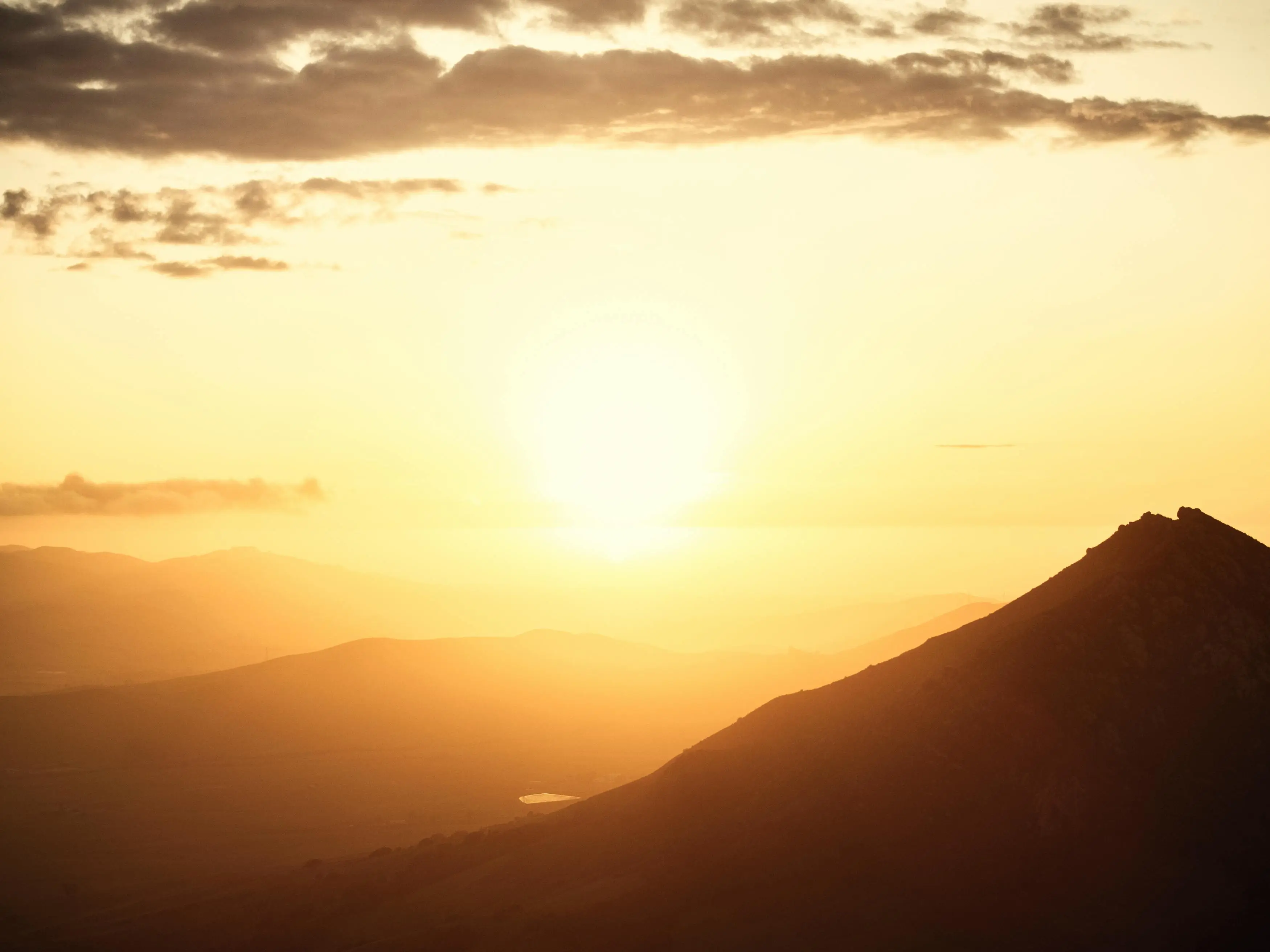 golden sunlight shining behind a mountainous landscape